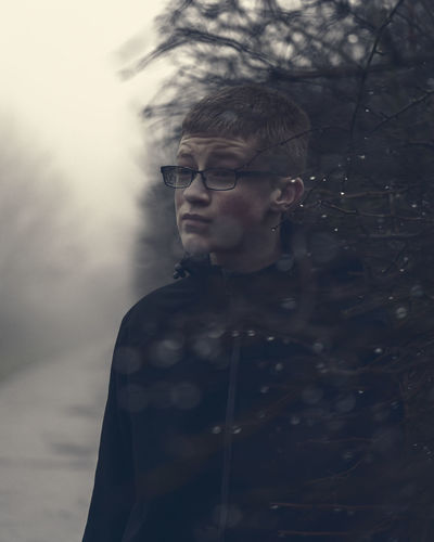 Boy wearing eyeglasses looking away while standing outdoors