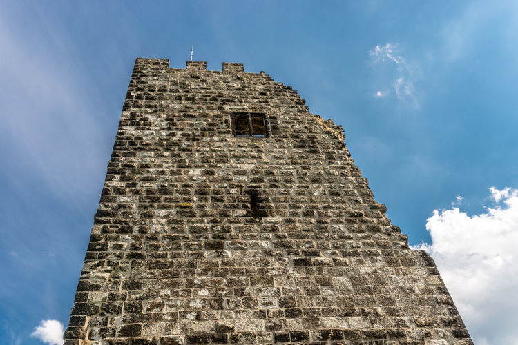 The ruins of a historical tower against a blue sky with white clouds.