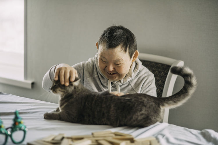 Elderly woman with down syndrome smiling and petting her mature domestic animal