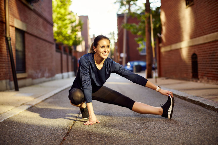 An athletic woman stretching in the city.