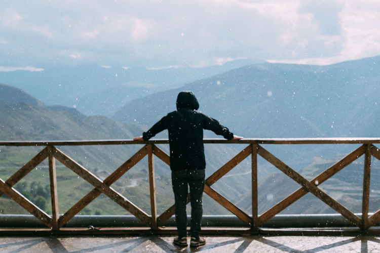 Low angle view of man standing by railing against mountain