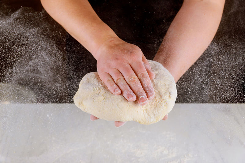 Close-up of woman kneading dough at kitchen counter