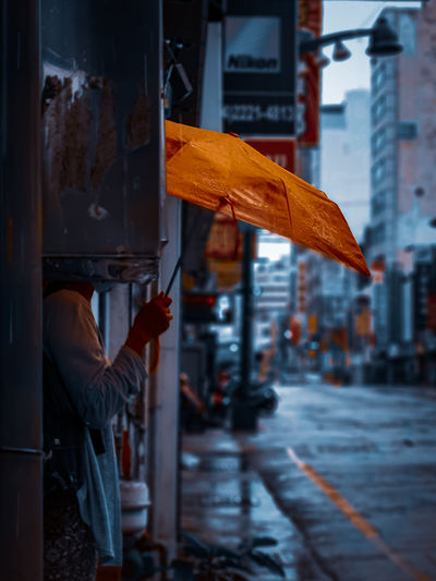 Man holding umbrella standing on wet street in rainy season