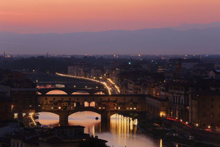 Ponte vecchio over arno river against sky during sunset