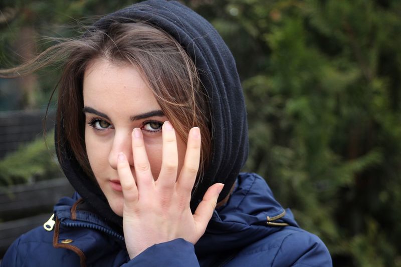 Close-up portrait of beautiful young woman with hand on face