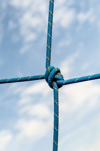 Low angle view of rope tied on fence against sky