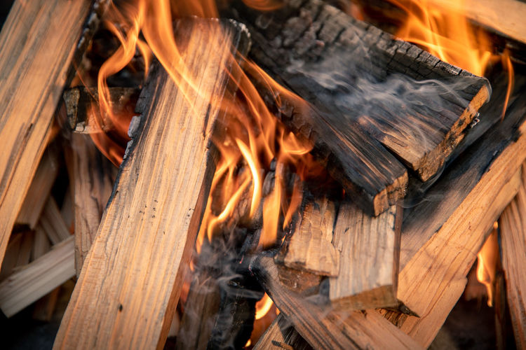 Closeup of pyre of burning wood with flames. production of charcoal for grilling meat wood logs burn
