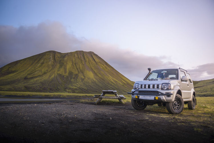 4x4 parked next to picnic table in front of mountain next to river