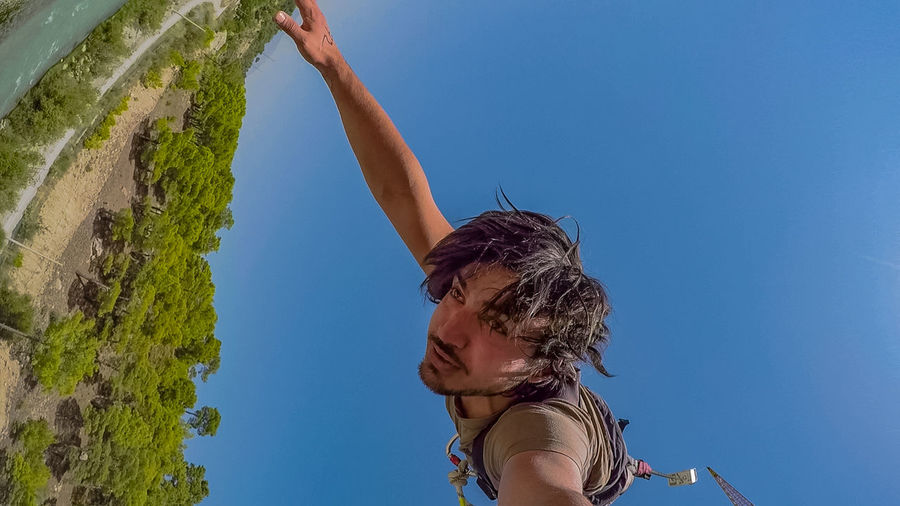 Low angle view of man hanging against clear sky
