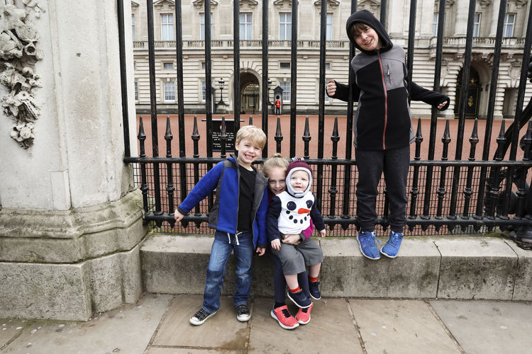 Four siblings sit at the gate of buckingham palace