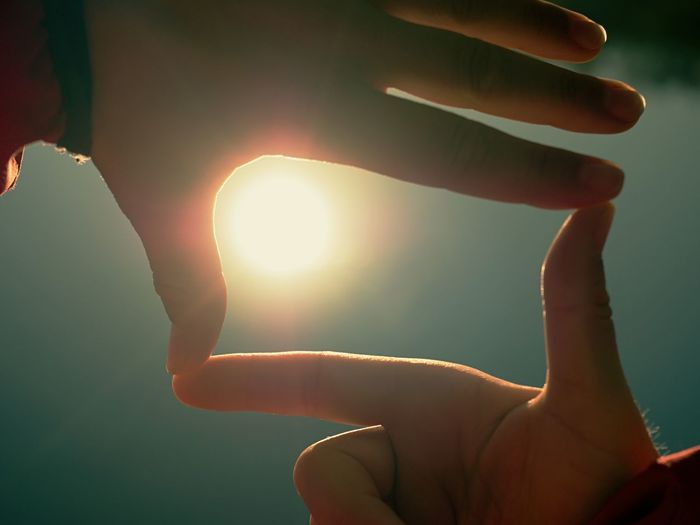 Sun on female hand. silhouette of hand holding sun. sun low above water level. lovely shadow play.