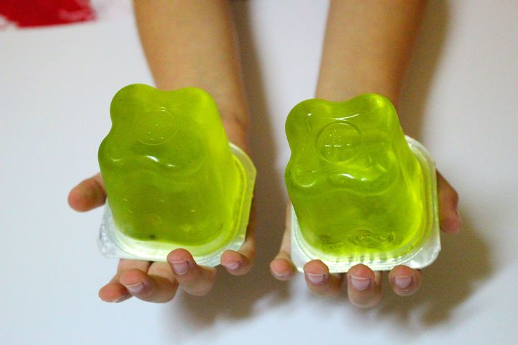 Cropped image of hand holding jelly in container