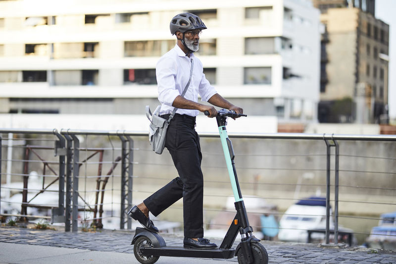 Mature businessman riding e-scooter