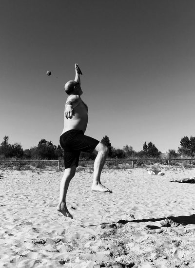 Full length of man jumping on beach against clear sky
