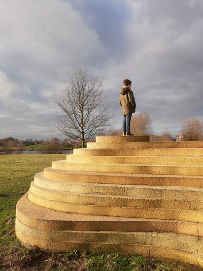 Man standing by staircase on field against sky
