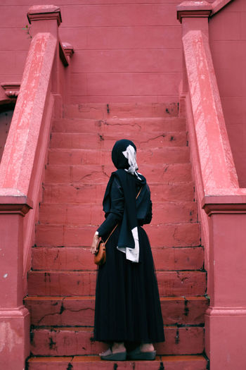 Rear view of woman in hijab standing on steps outdoors