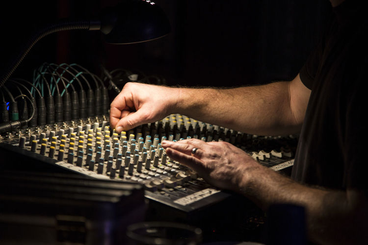 Midsection of man using sound mixer in recording studio