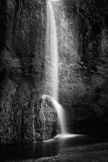 Waterfall from above on the rock, made up of dark basalt banks, forming