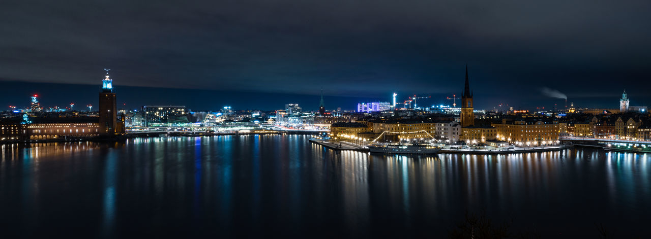 Illuminated buildings in stockholm city at night with reflections in waterfront