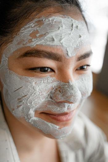 Close-up of smiling woman with facial mask looking away