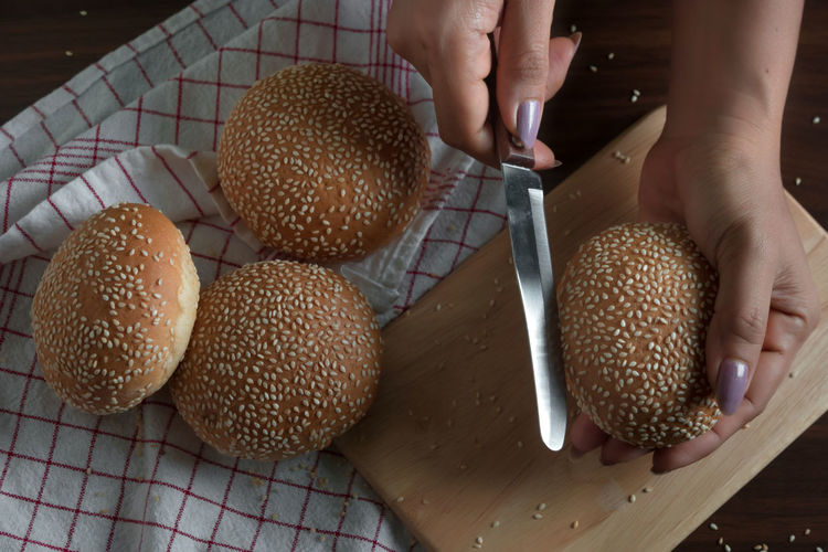 Cropped hands of woman cutting sesame seed buns