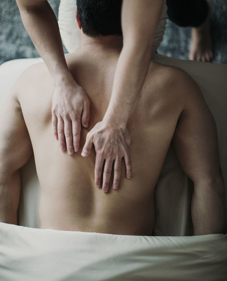 Close up of female hands on male back on massage table from above