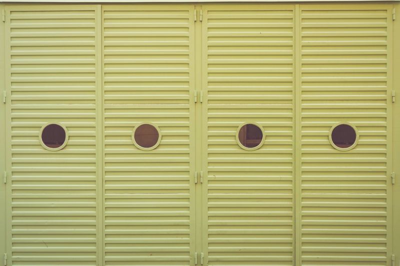 Round windows portholes on green garage door 