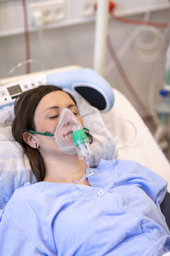 High angle view of patient wearing oxygen mask while sleeping on bed in hospital