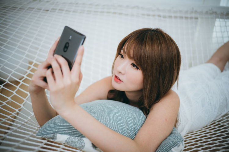 Portrait of woman using mobile phone on bed