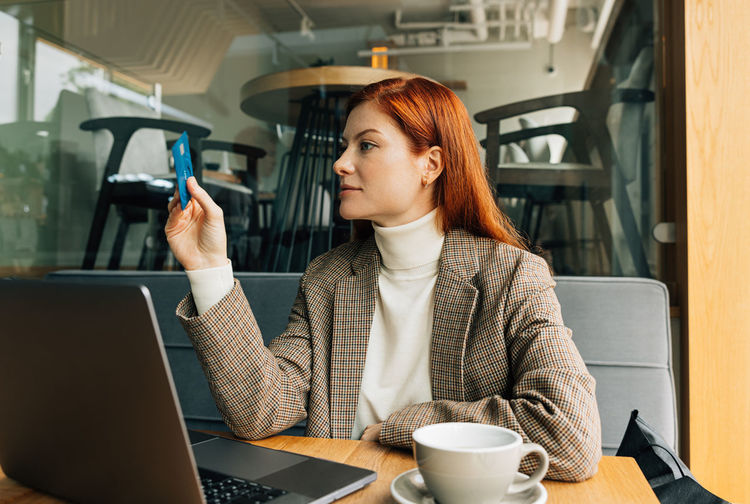 Young woman using mobile phone while sitting in cafe