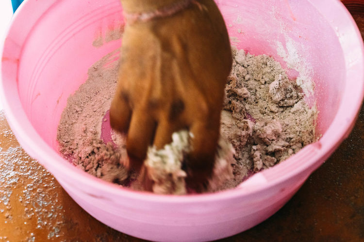 Cropped image of hand making herbal medicine in pink bucket