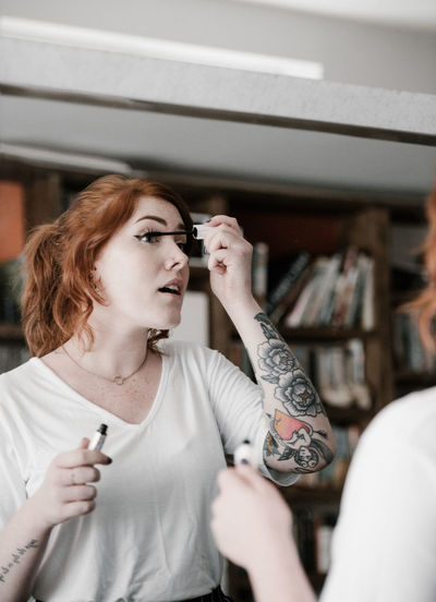 Young woman applying make-up at home