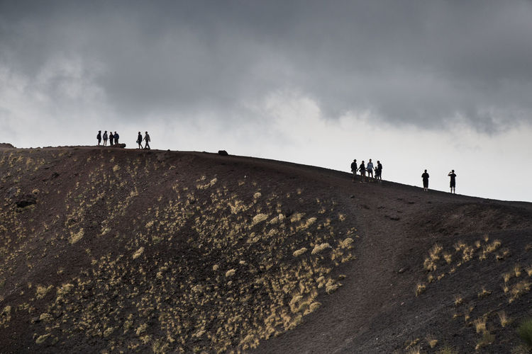Low angle view of people walking on volcano mountain against sky