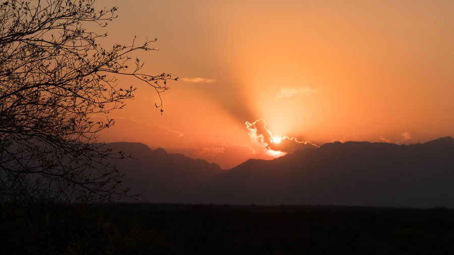 Scenic view of silhouette mountains against orange sky