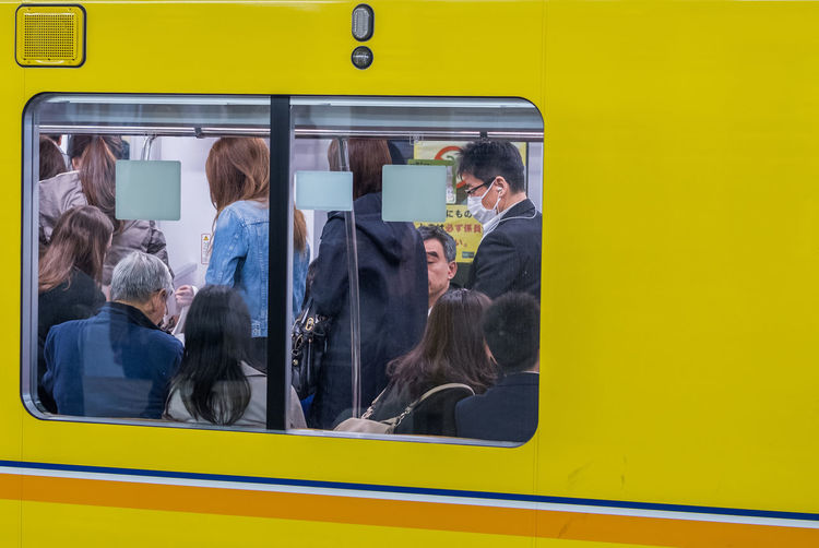People in yellow train seen through window