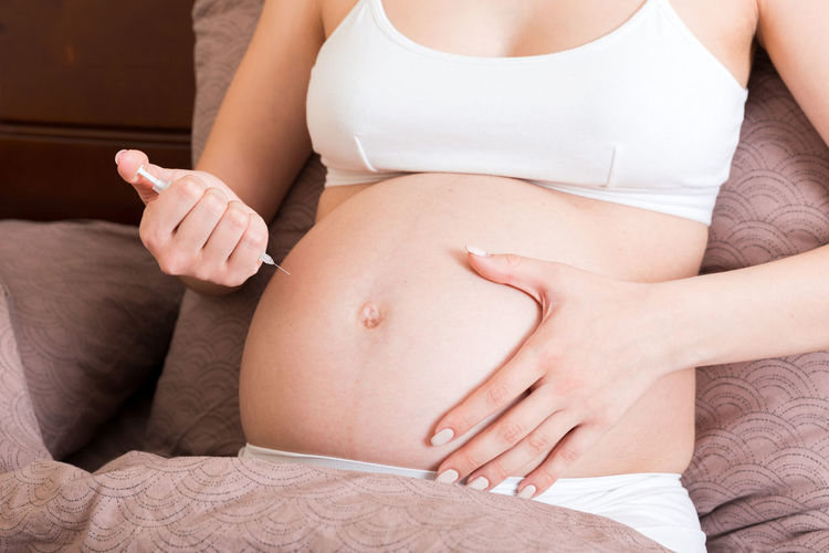 Pregnant woman with insulin syringe in home on bed. pregnant diabetes concept.