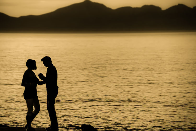 Couple on seashore during sunset