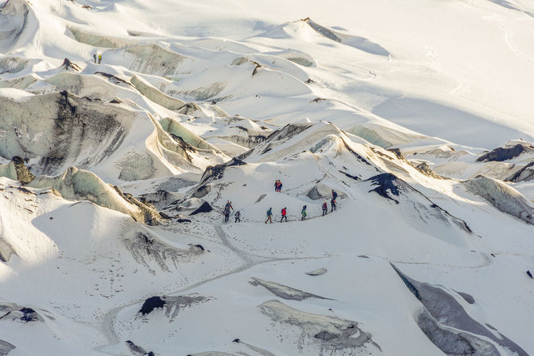 Aerial view of people walking on snow covered mountain