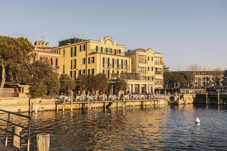 Buildings by river against clear sky