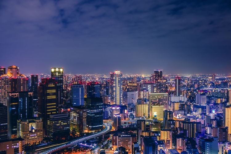 Illuminated buildings in osaka city against sky at night