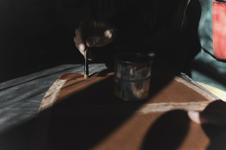 Man varnishing leather in darkness