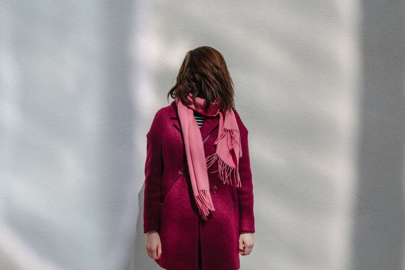 Woman with face hidden by hair standing against wall