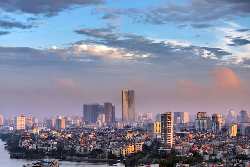 Modern buildings in city against sky during sunset