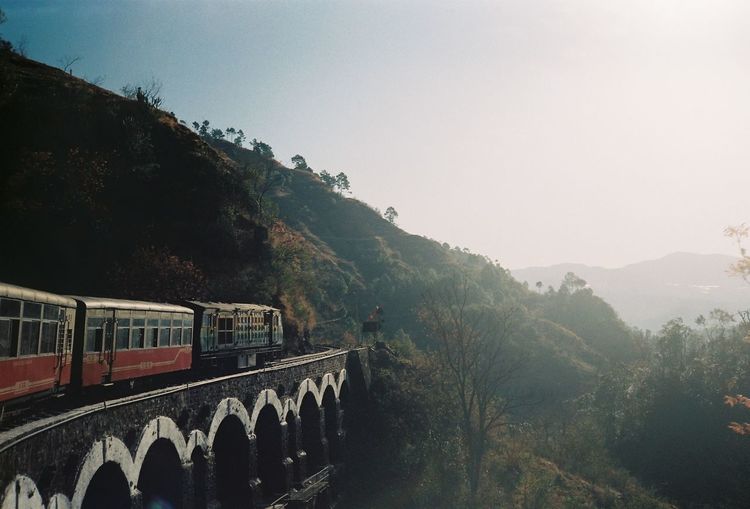Train on mountain bridge against sky
