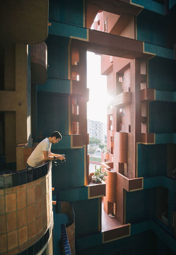 Side view of male standing on balcony of contemporary residential apartment building with geometric walls in barcelona