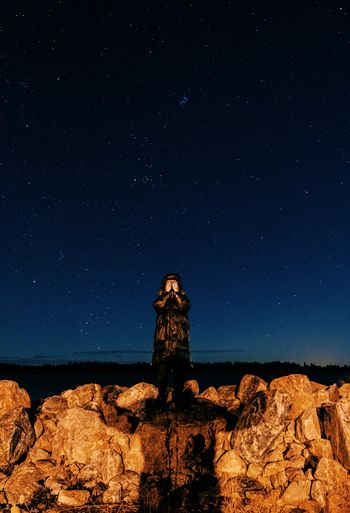 Low angle view of rock formation and a person against sky at night
