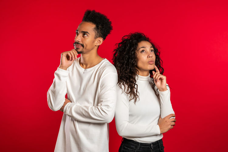 Young couple looking away against red background
