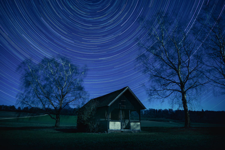 Idyllic barn against hypnotic night sky with dreamy star trails