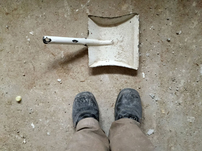 Low section of man standing by work tool on floor