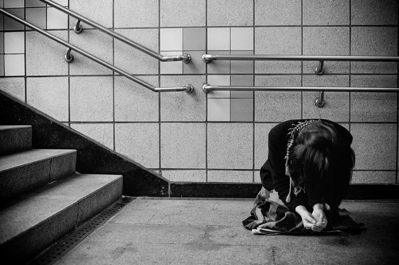 Woman kneeling against wall at underground walkway